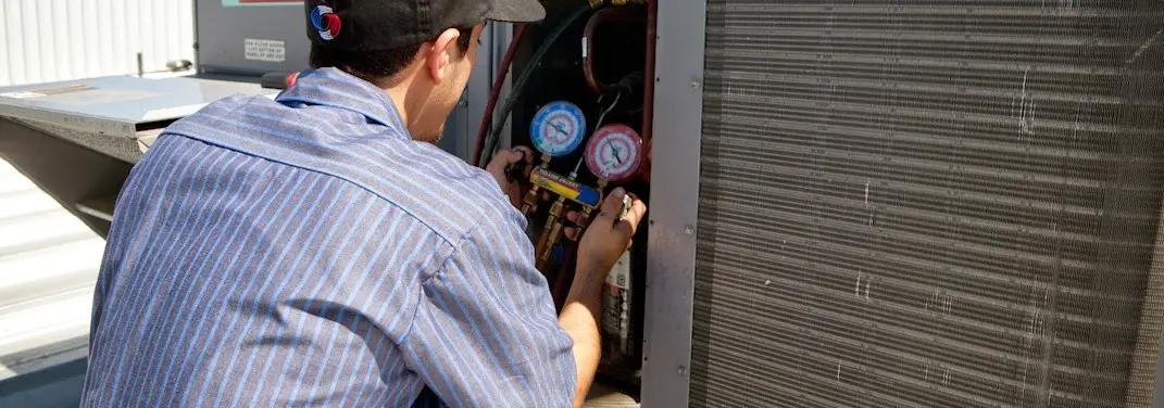 HVAC technician servicing a condenser unit in Douglass